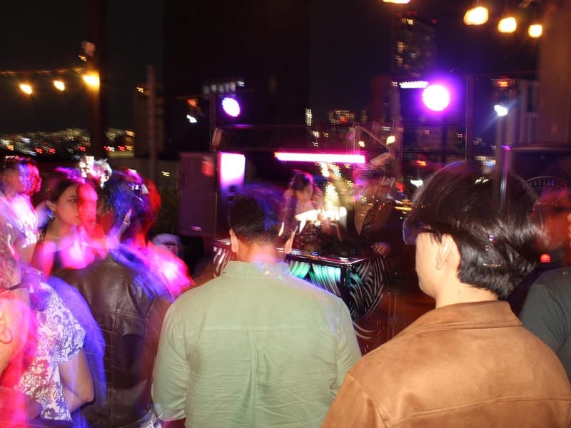 DJ en tarima con crowd levantando las manos
